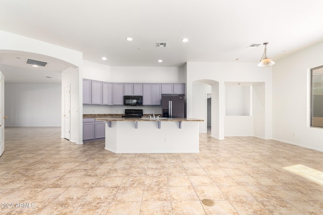 kitchen with gray cabinets, an island with sink, a kitchen bar, black appliances, and decorative light fixtures