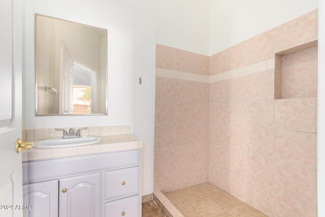 bathroom featuring tiled shower and vanity