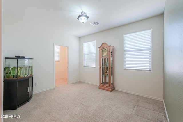 empty room with baseboards, carpet floors, and visible vents