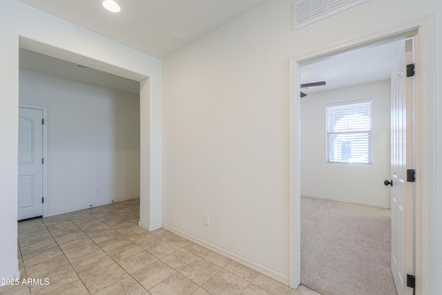 spare room with baseboards, visible vents, light tile patterned flooring, and light colored carpet