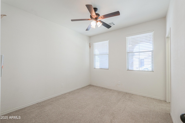 spare room with baseboards, ceiling fan, visible vents, and light colored carpet