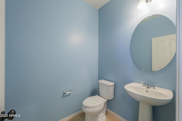 half bathroom featuring tile patterned floors, toilet, and baseboards