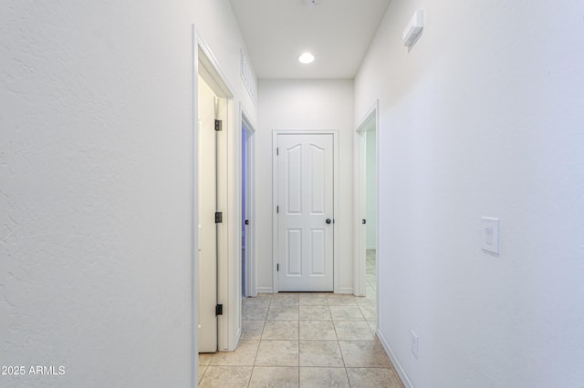 corridor featuring light tile patterned floors and baseboards