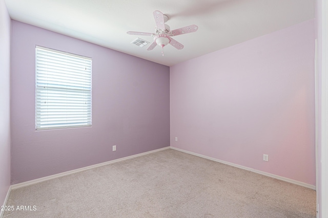 empty room featuring carpet, visible vents, and a ceiling fan