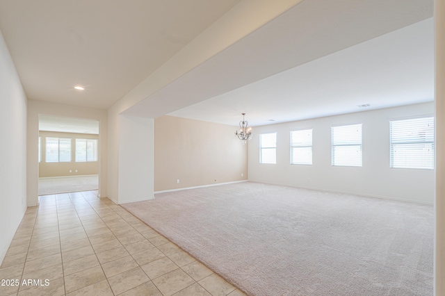 unfurnished room featuring a healthy amount of sunlight, a chandelier, light tile patterned floors, and light carpet