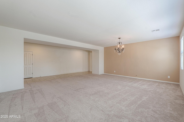 carpeted spare room featuring baseboards, visible vents, and a chandelier