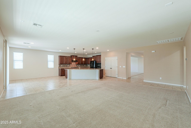 unfurnished living room featuring light carpet, visible vents, recessed lighting, and light tile patterned floors
