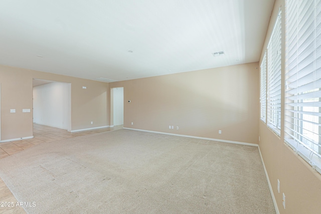 unfurnished room with baseboards, visible vents, and light colored carpet
