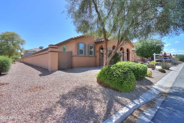 view of front of home featuring a tiled roof, stucco siding, and a fenced front yard