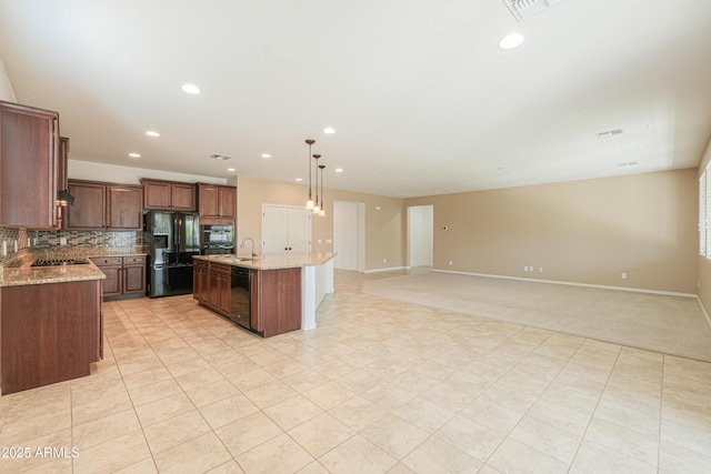kitchen with an island with sink, black appliances, open floor plan, and tasteful backsplash