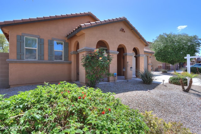 mediterranean / spanish-style home with a tiled roof, stucco siding, and an attached garage