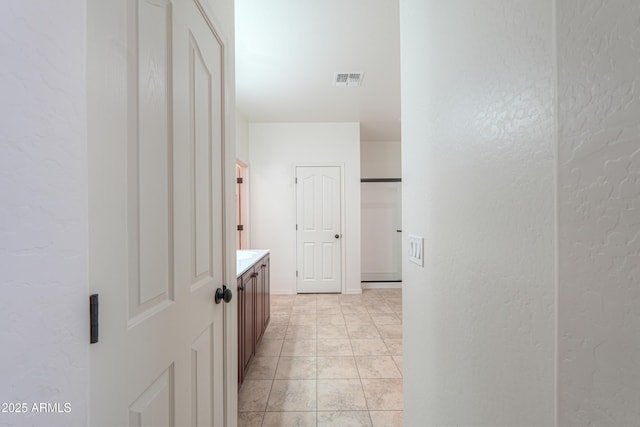 corridor featuring visible vents and a textured wall