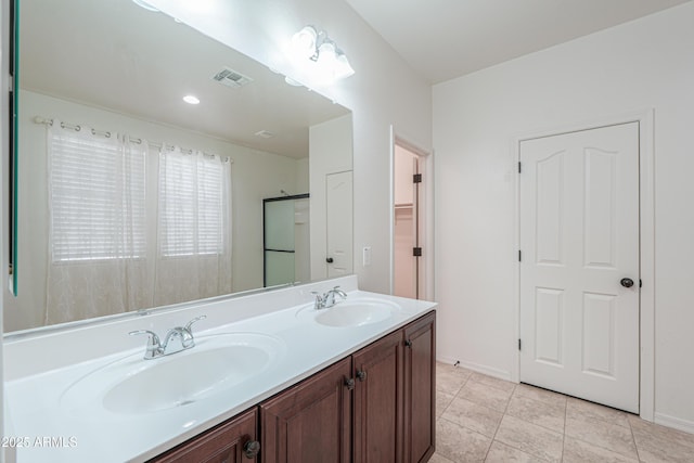 full bath featuring an enclosed shower, visible vents, a sink, and double vanity