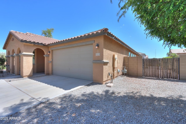 view of front of home with driveway, stucco siding, a tiled roof, and a garage