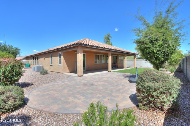 rear view of property featuring a tile roof, stucco siding, a fenced backyard, central AC unit, and a patio area