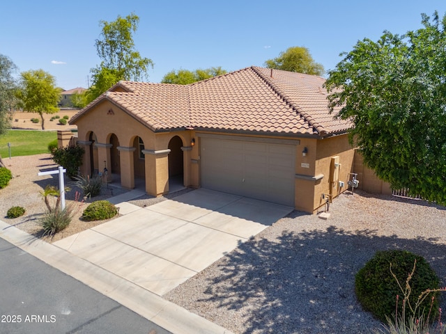 mediterranean / spanish house with stucco siding, a tiled roof, a garage, and concrete driveway