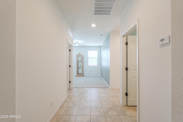 hall with light tile patterned flooring, baseboards, and visible vents