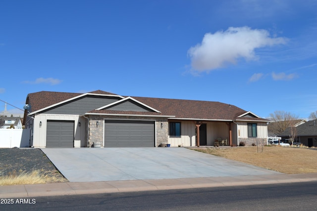 single story home featuring a garage, driveway, stone siding, fence, and board and batten siding