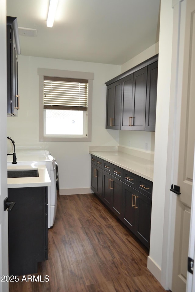 laundry room with dark wood finished floors, washing machine and clothes dryer, cabinet space, and baseboards