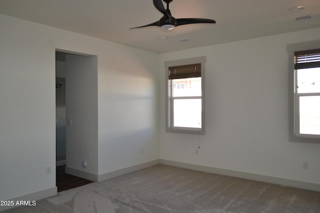 carpeted spare room with a ceiling fan, visible vents, and baseboards