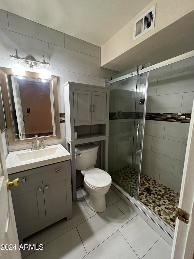 bathroom with vanity, toilet, tile patterned flooring, and a shower with door