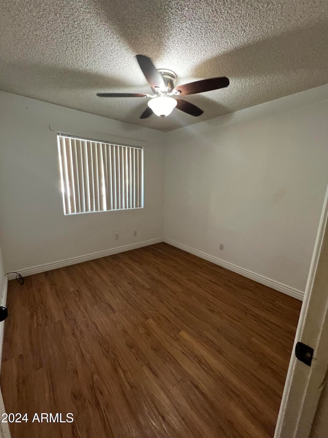 spare room with ceiling fan, a textured ceiling, and dark hardwood / wood-style flooring