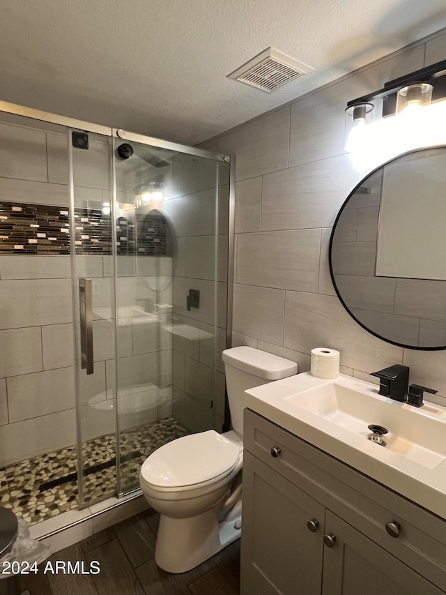 bathroom featuring hardwood / wood-style floors, a shower with door, a textured ceiling, toilet, and vanity