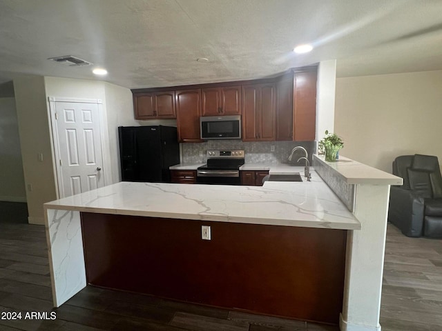 kitchen featuring dark hardwood / wood-style floors, backsplash, sink, light stone countertops, and appliances with stainless steel finishes