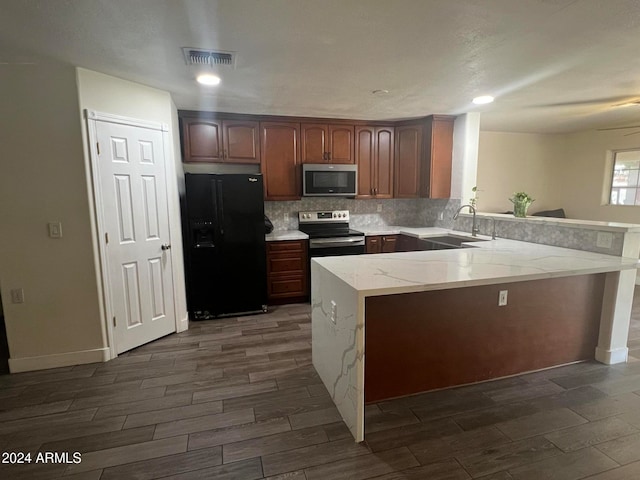 kitchen featuring kitchen peninsula, tasteful backsplash, appliances with stainless steel finishes, dark wood-type flooring, and sink