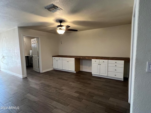 interior space featuring built in desk, ceiling fan, a textured ceiling, and dark hardwood / wood-style flooring