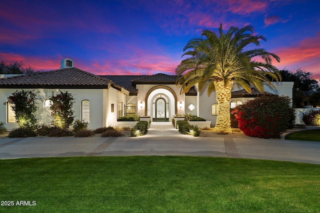 mediterranean / spanish-style home with concrete driveway, a front yard, and a tile roof