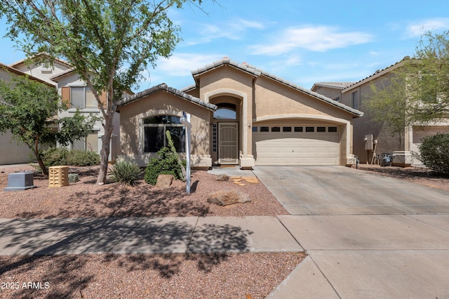 mediterranean / spanish house with a garage, stucco siding, driveway, and a tile roof