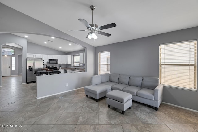 living room with ceiling fan, arched walkways, recessed lighting, baseboards, and vaulted ceiling