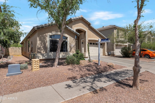 mediterranean / spanish house with a tiled roof, fence, concrete driveway, an attached garage, and stucco siding