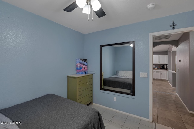bedroom with arched walkways, baseboards, a ceiling fan, and light tile patterned flooring