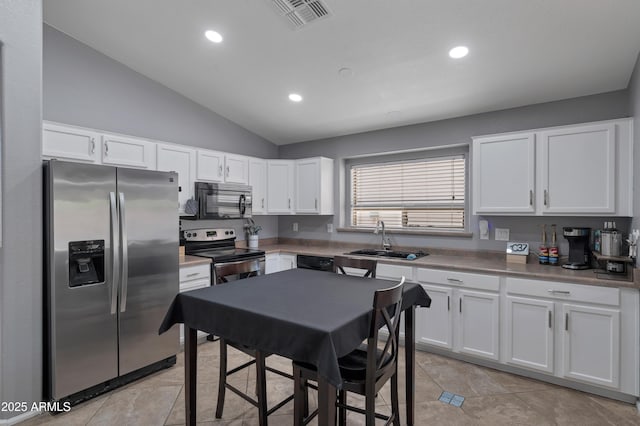 kitchen with visible vents, appliances with stainless steel finishes, a sink, lofted ceiling, and white cabinetry