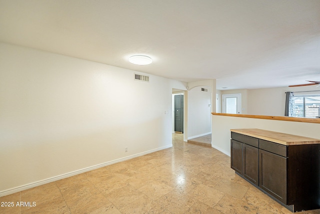 kitchen featuring visible vents, wooden counters, a ceiling fan, dark brown cabinetry, and baseboards