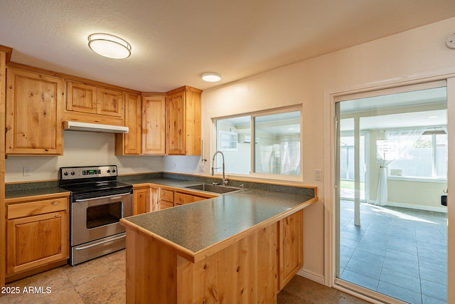 kitchen featuring dark countertops, a peninsula, stainless steel electric stove, under cabinet range hood, and a sink