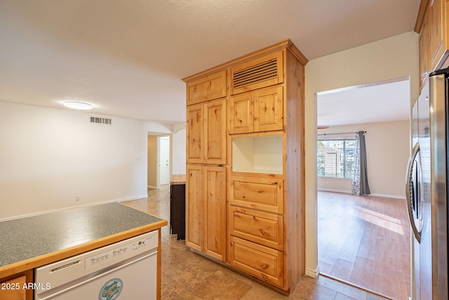 kitchen with baseboards, visible vents, freestanding refrigerator, white dishwasher, and light wood-type flooring