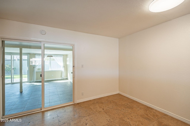 empty room featuring stone tile floors and baseboards