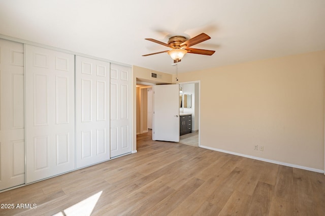 unfurnished bedroom featuring light wood-style flooring, a closet, visible vents, and baseboards