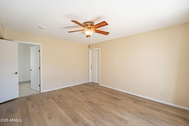 spare room featuring a ceiling fan, light wood-style flooring, and baseboards