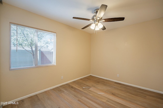 spare room with light wood-type flooring, a ceiling fan, and baseboards