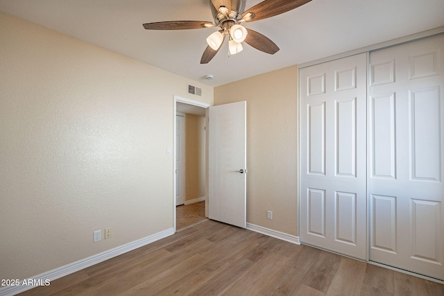 unfurnished bedroom featuring ceiling fan, wood finished floors, visible vents, baseboards, and a closet