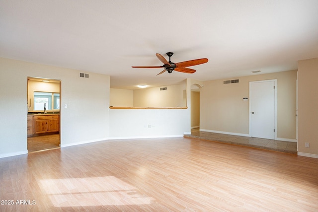 unfurnished living room featuring light wood-style floors, visible vents, and a sink