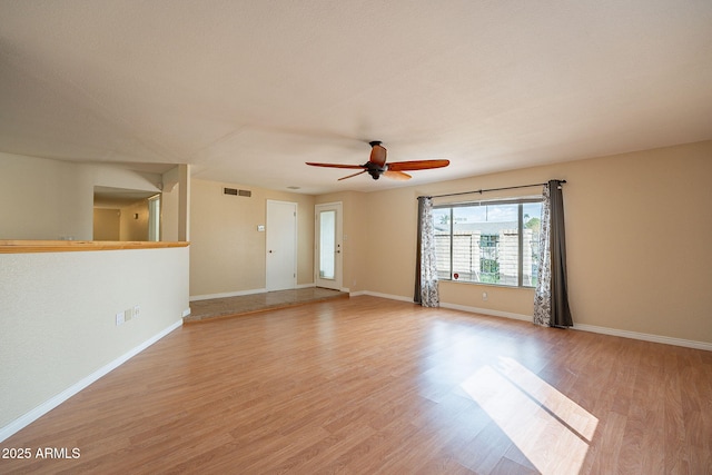 empty room with a ceiling fan, visible vents, baseboards, and wood finished floors