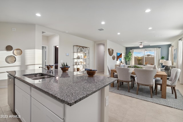 kitchen featuring ceiling fan, sink, stainless steel dishwasher, dark stone countertops, and white cabinets