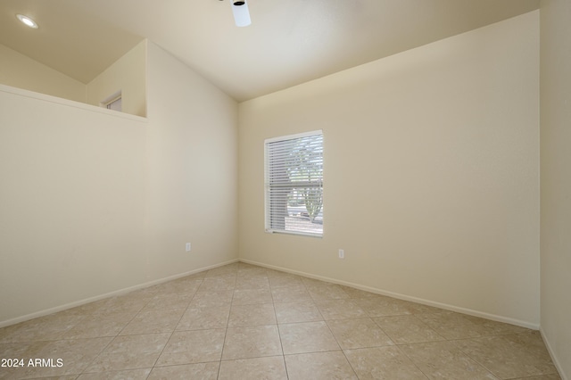 tiled empty room featuring vaulted ceiling