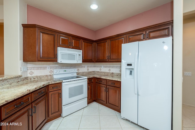 kitchen with decorative backsplash, light tile patterned floors, light stone counters, and white appliances