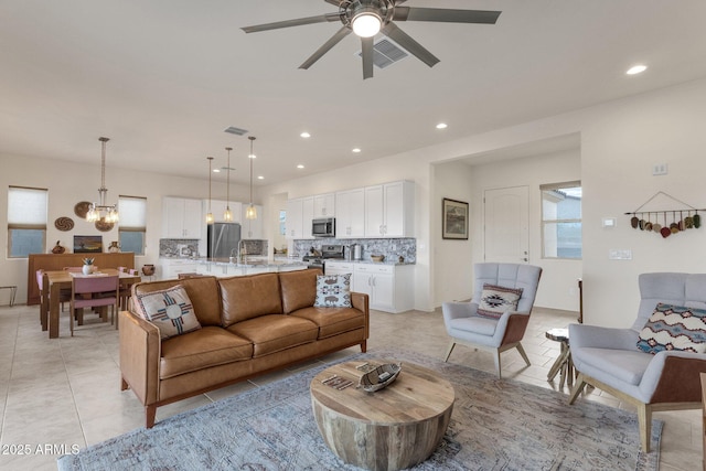 tiled living room featuring sink and ceiling fan with notable chandelier